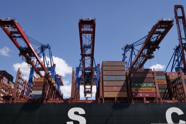 Guindastes pórtico carregando contêineres em um navio no porto, vistos a partir do cais